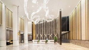 A spacious lobby with a modern reception desk, vertical wooden panels, and a decorative ceiling feature. - Venus Resort & Restaurant (Chongzuo)