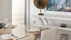 A dining table with chairs, a wine glass, plates, and cutlery. - Surf Watch Mollymook (Mollymook Beach)