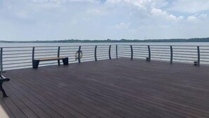 A wooden deck with a railing overlooking a body of water. - Mingzhu Lake Swan Garden Resort (Shanghai)