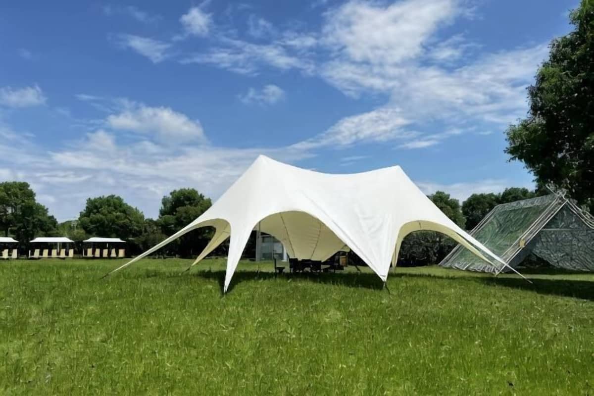 A white tent-like structure on a grassy field.