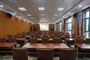 A conference room with rows of tables and chairs, large windows, and a stage at the front. - Mingzhu Lake Swan Garden Resort (Shanghai)