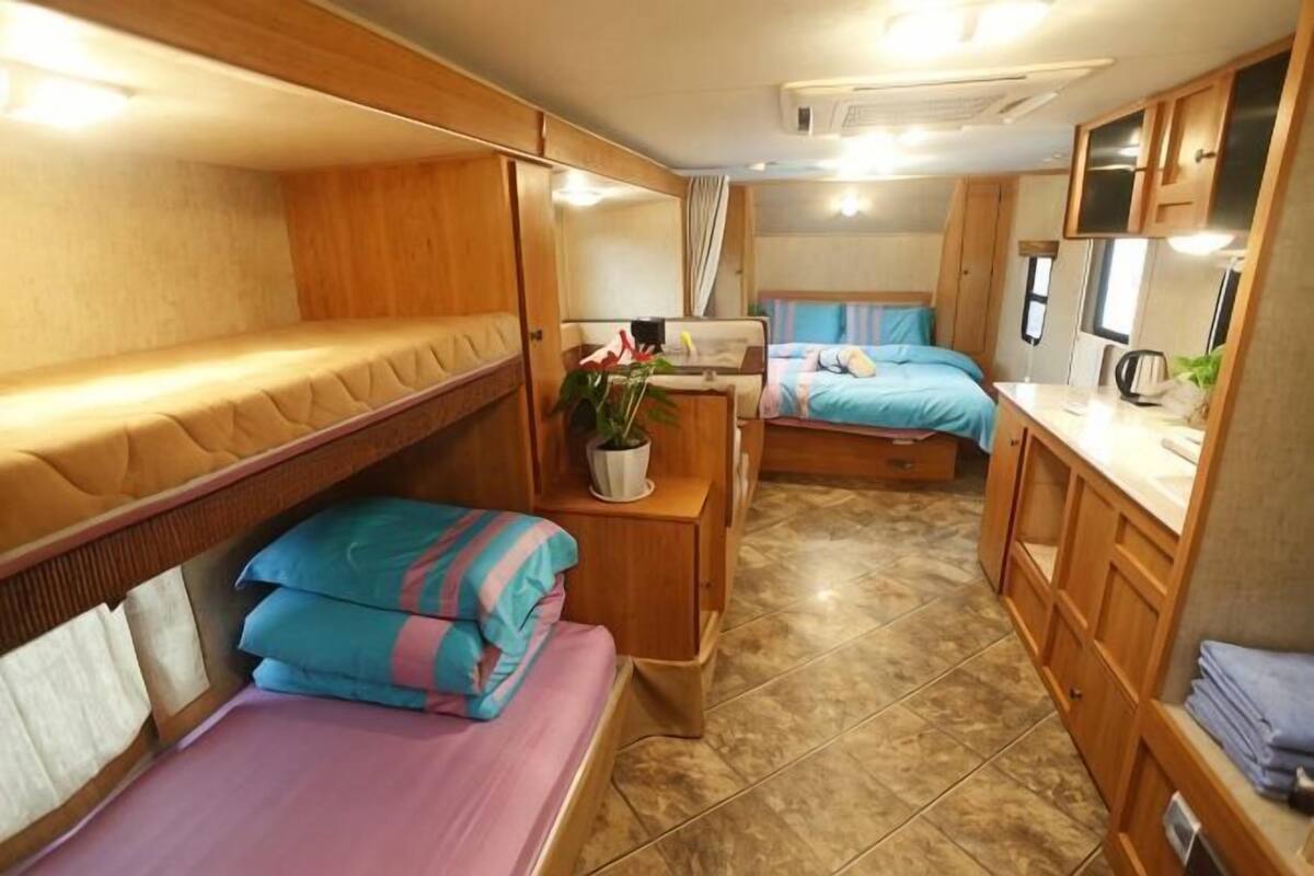 Ein kompaktes Wohnmobil-Interieur mit Etagenbetten, einer Küchenzeile und einem Badezimmer.