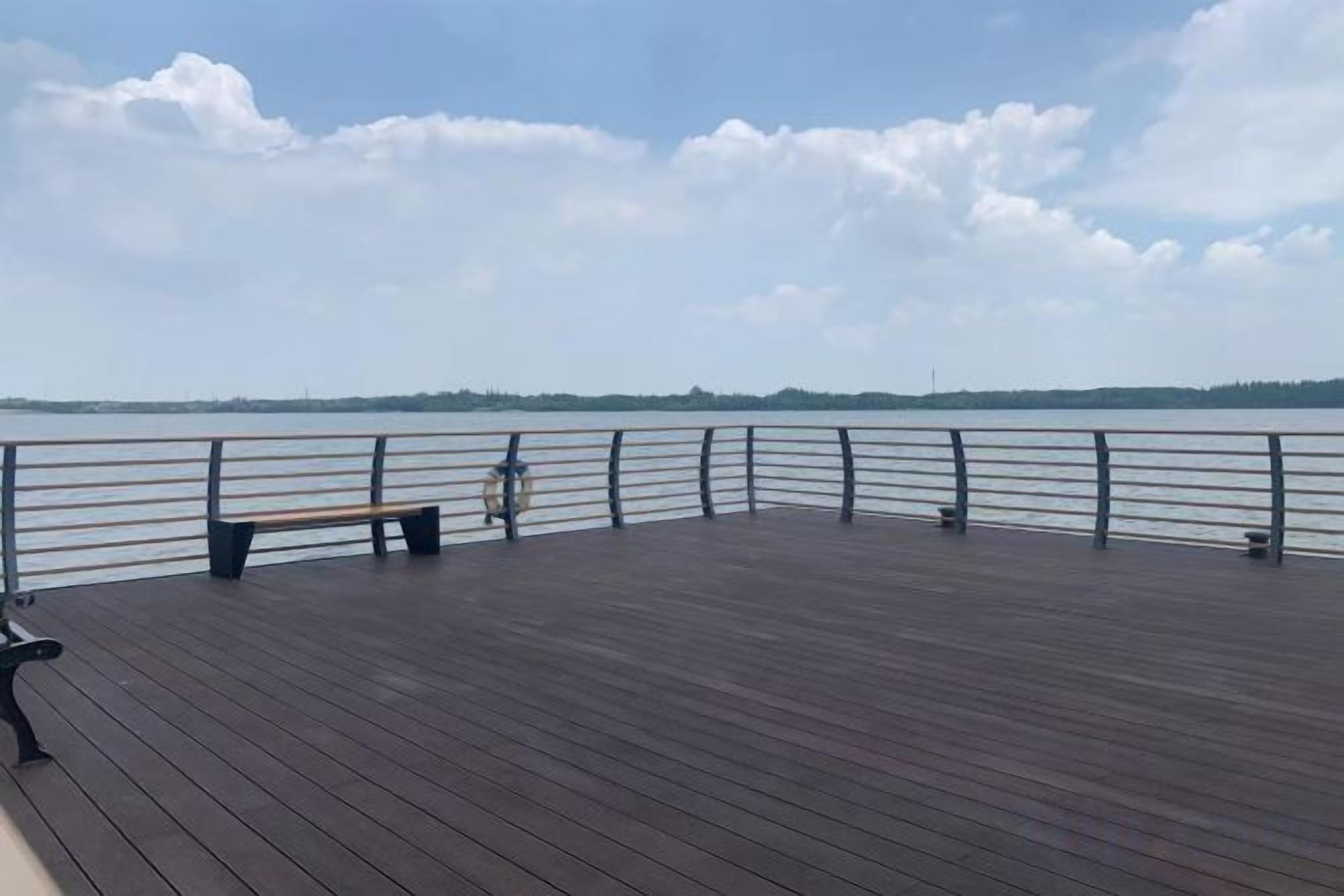 A wooden deck with a railing overlooking a body of water.