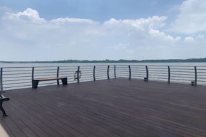 Une terrasse en bois avec une balustrade donnant sur une étendue d’eau.