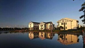 A row of modern, two-story houses with a large body of water in front. - Mingzhu Lake Swan Garden Resort (Shanghai)