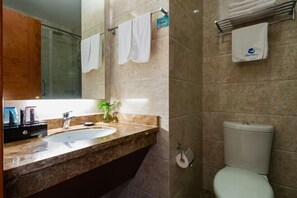 Un baño con lavamanos, espejo, toallero y retrete.