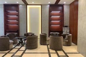 Un hall d’entrée avec des sièges, un comptoir de réception et un panneau lumineux vertical.