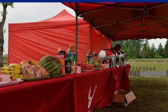 Een rode tent met een tafel waarop eten en drinken staan.