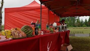 Een rode tent met een tafel waarop eten en drinken staan.