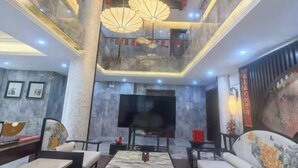 A hotel lobby with a high ceiling, marble walls, a large flat-screen TV, and traditional lanterns. - Mingzhu Lake Swan Garden Resort (Shanghai)