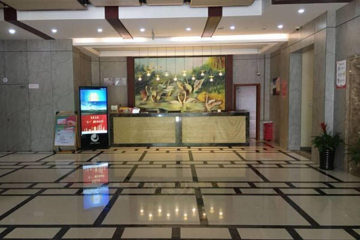 Eine Hotelhalle mit einer Rezeption, einem digitalen Informationskiosk und einem Fliesenboden.