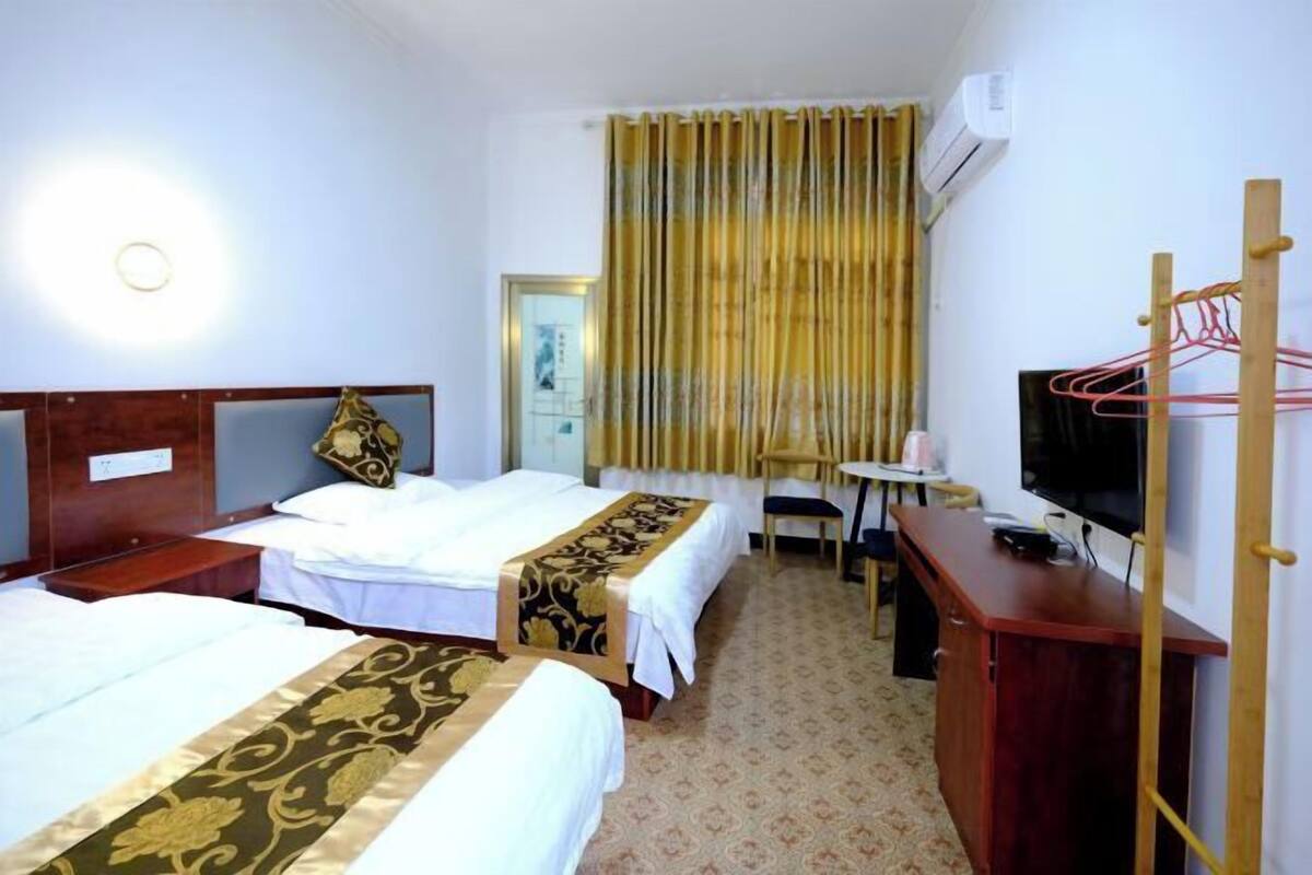A hotel room with two beds, a desk, a chair, a television, and a wardrobe.