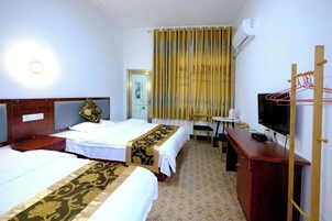 Una habitación de hotel con dos camas, un escritorio, una silla, un televisor y un armario.