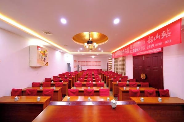 A conference room with rows of chairs, a podium, and a large red banner on the wall.