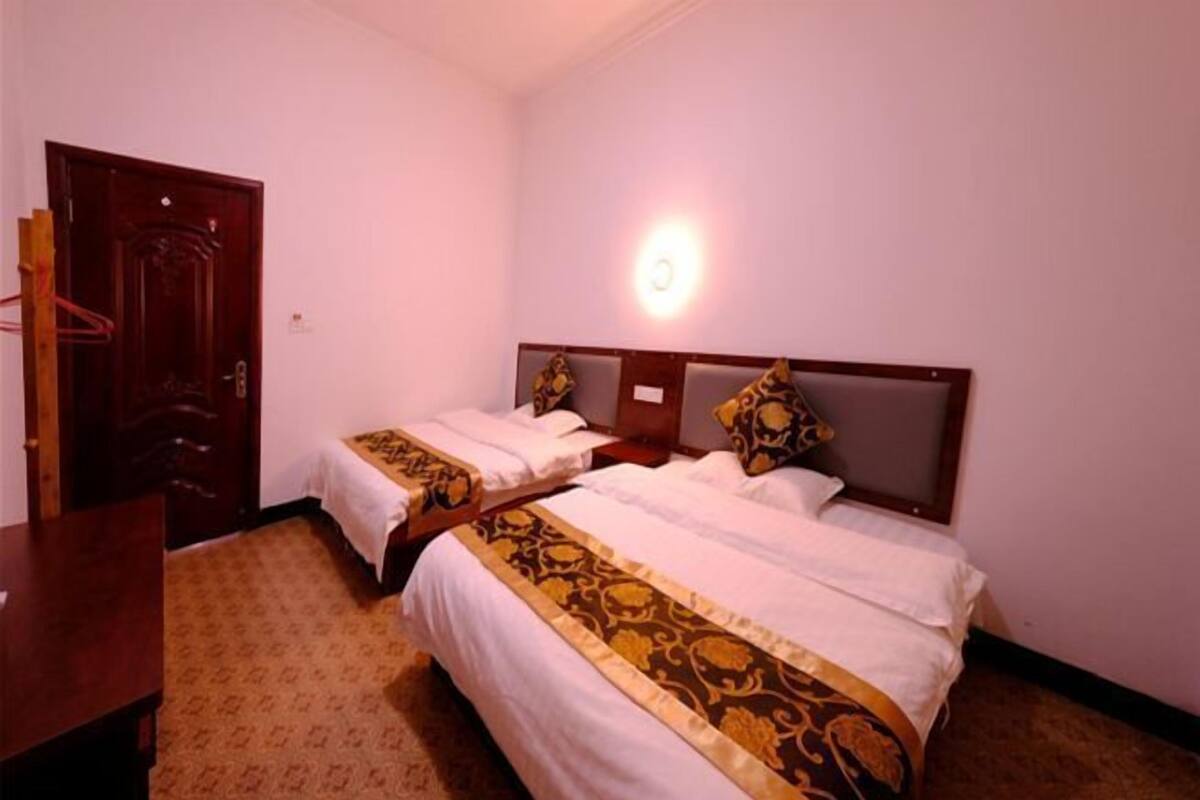 A hotel room with two beds, a wooden desk, and a door.