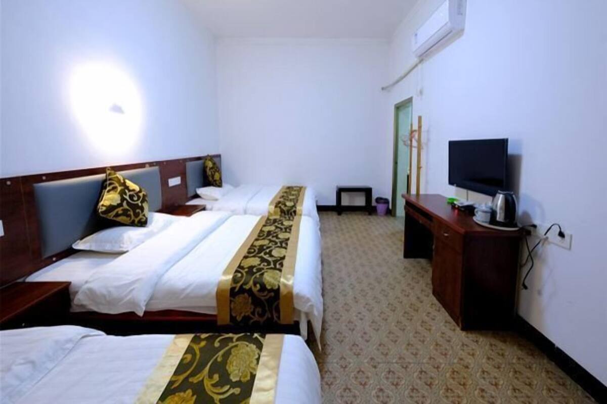 A hotel room with two beds, a television, a desk, and a wardrobe.