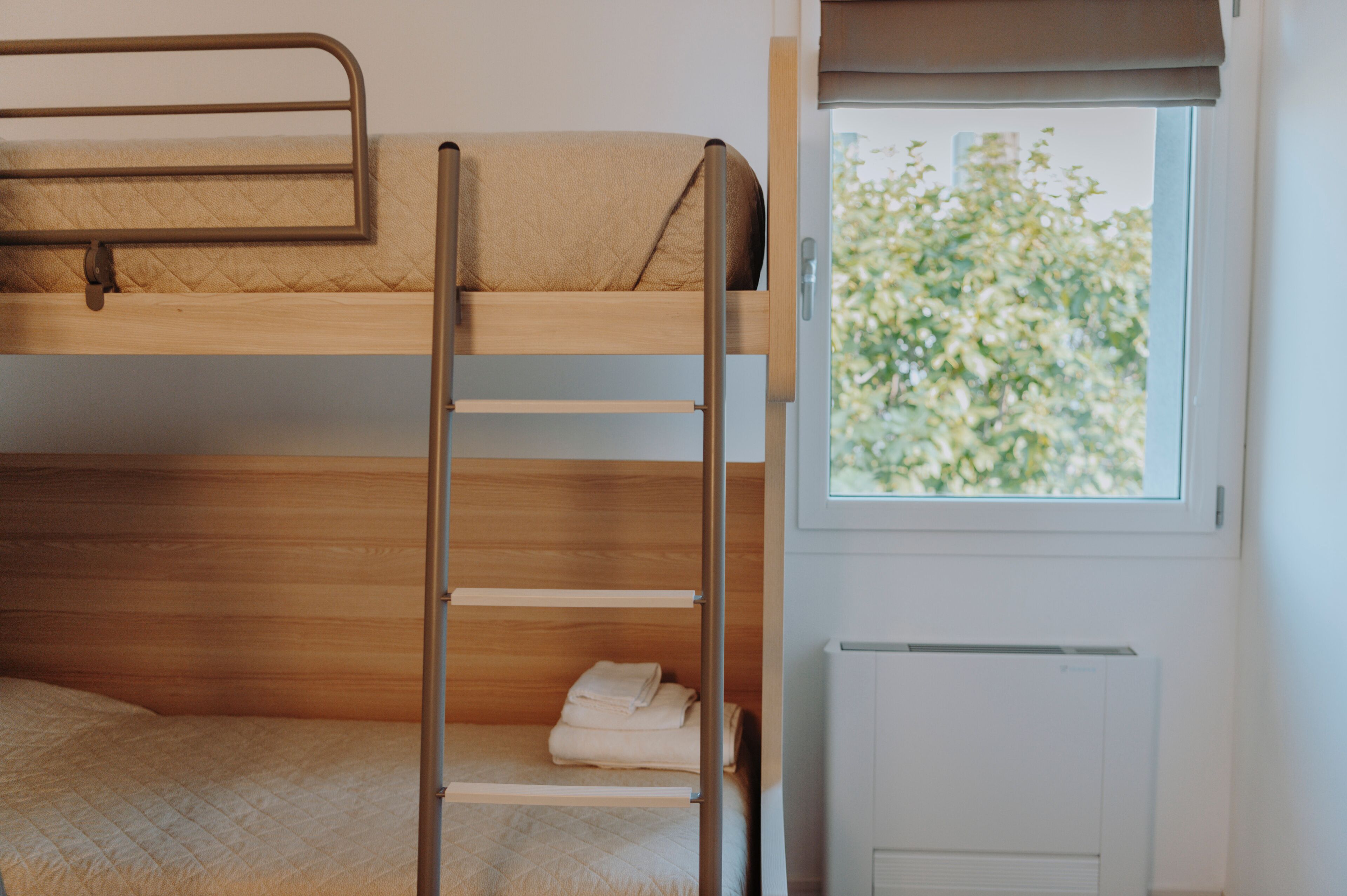 Habitación con literas, ventana y una toalla doblada cuidadosamente en la litera inferior.