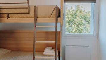 Habitación con literas, ventana y una toalla doblada cuidadosamente en la litera inferior.
