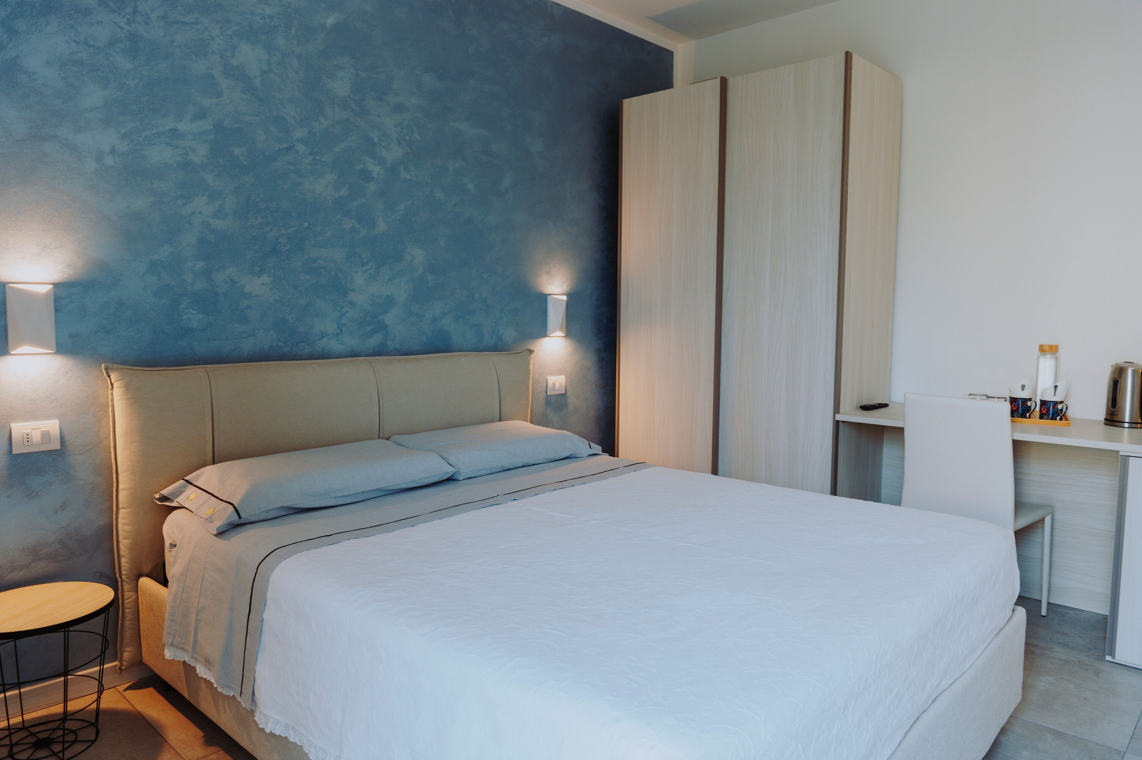 Un dormitorio moderno con una cama grande, lámparas de noche, un escritorio y un armario.