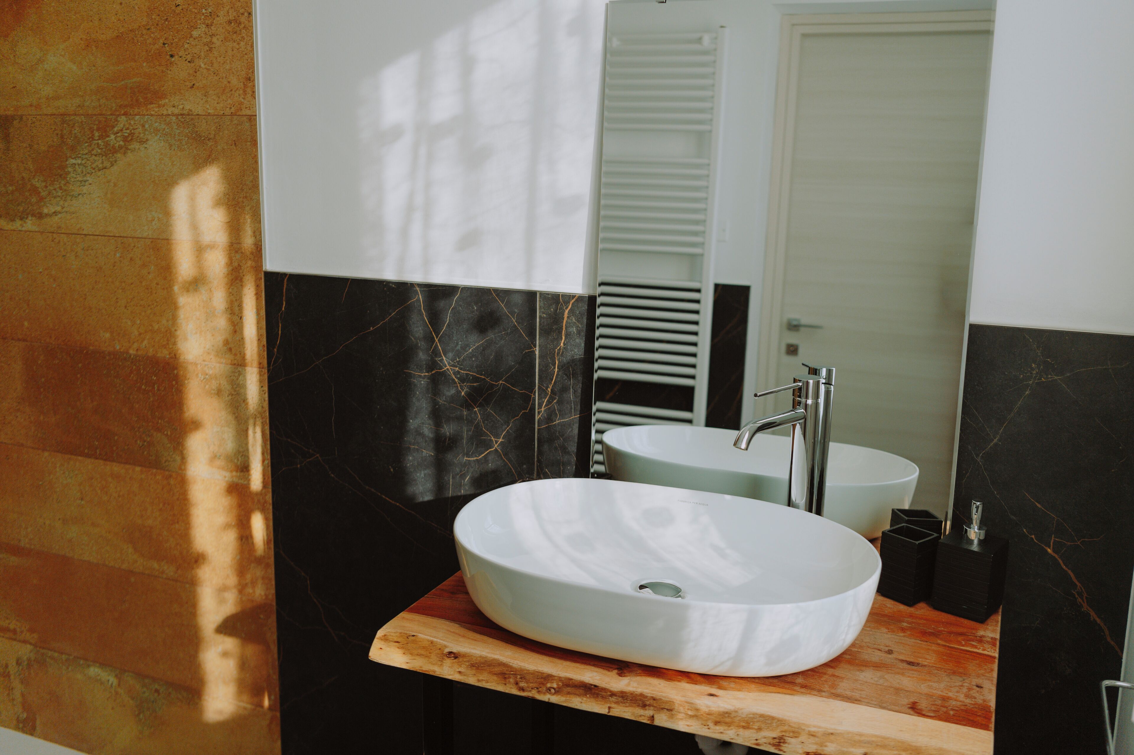 Un baño con tocador de madera, un lavamanos blanco y un espejo.