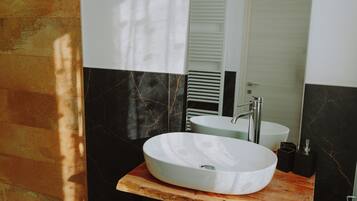 Un baño con tocador de madera, un lavamanos blanco y un espejo.