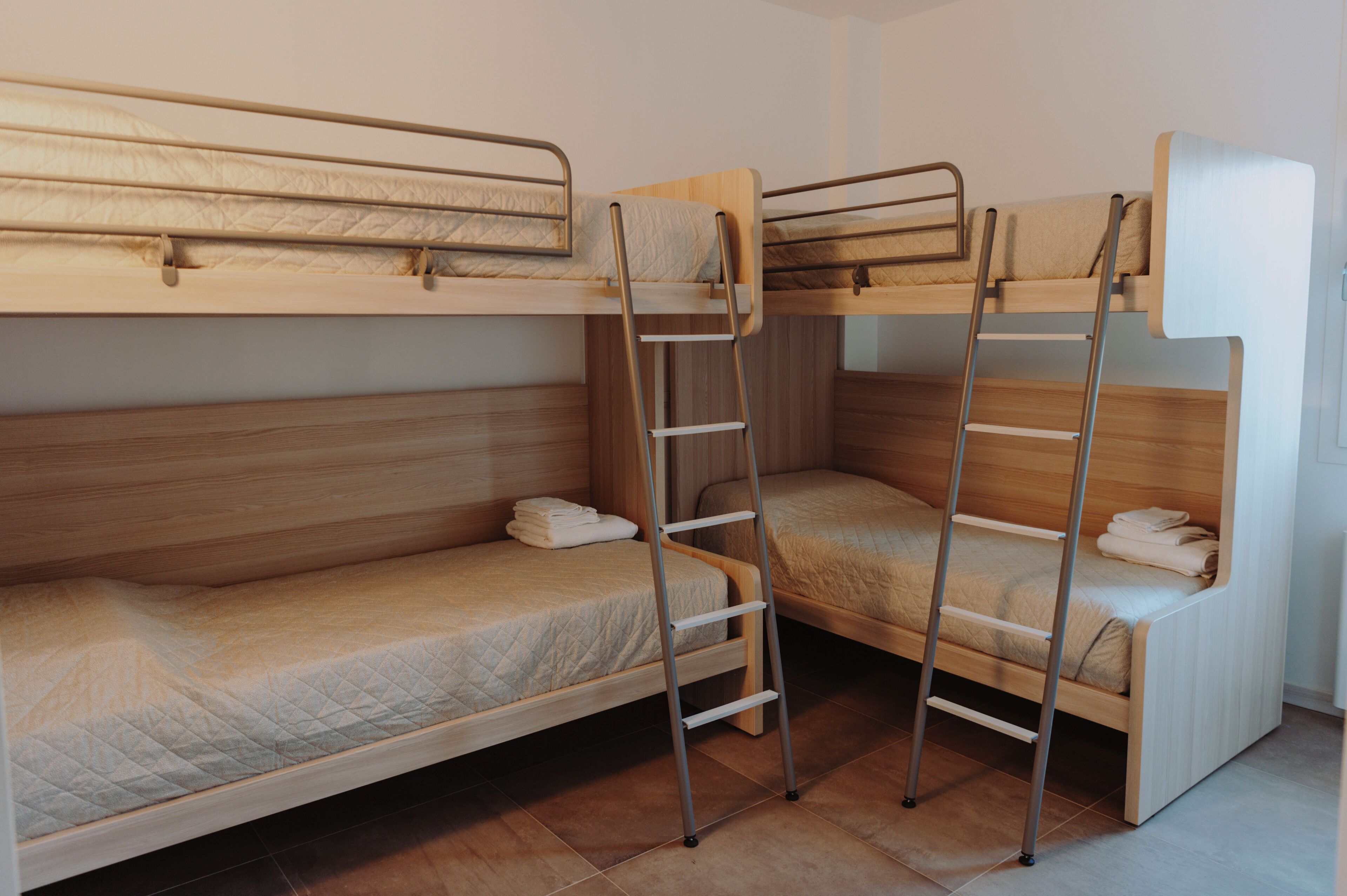 Habitación con literas, cabeceros de madera y escaleras de metal.