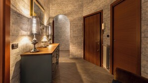 A hallway with stone walls, wooden doors, and a wooden counter with lamps. - Rome Elements Apartment, elegante, raffinato appartamento a 15 minuti dal centro (Roma)