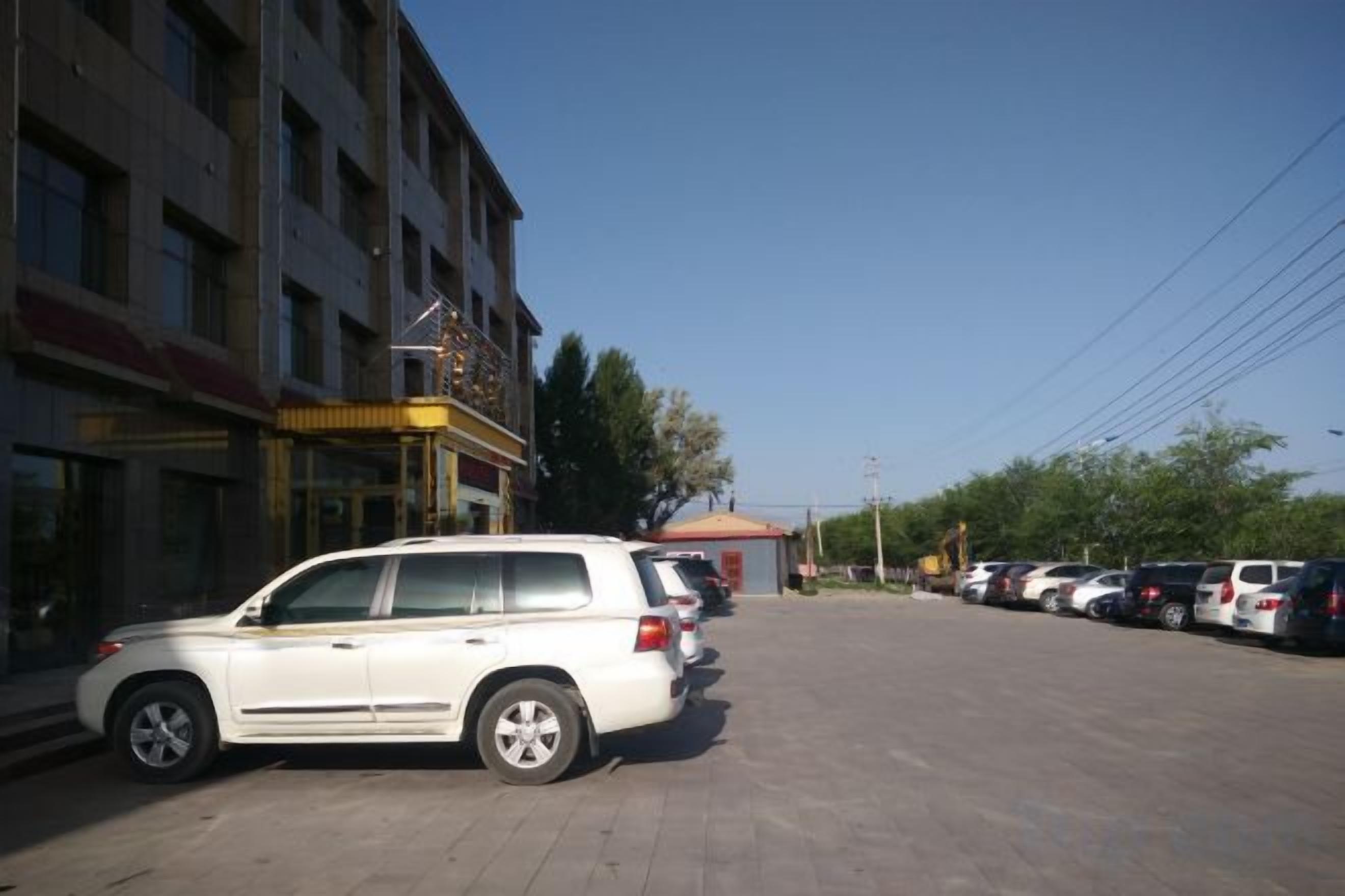 A parking lot with a white SUV parked in front of a building with a sign.