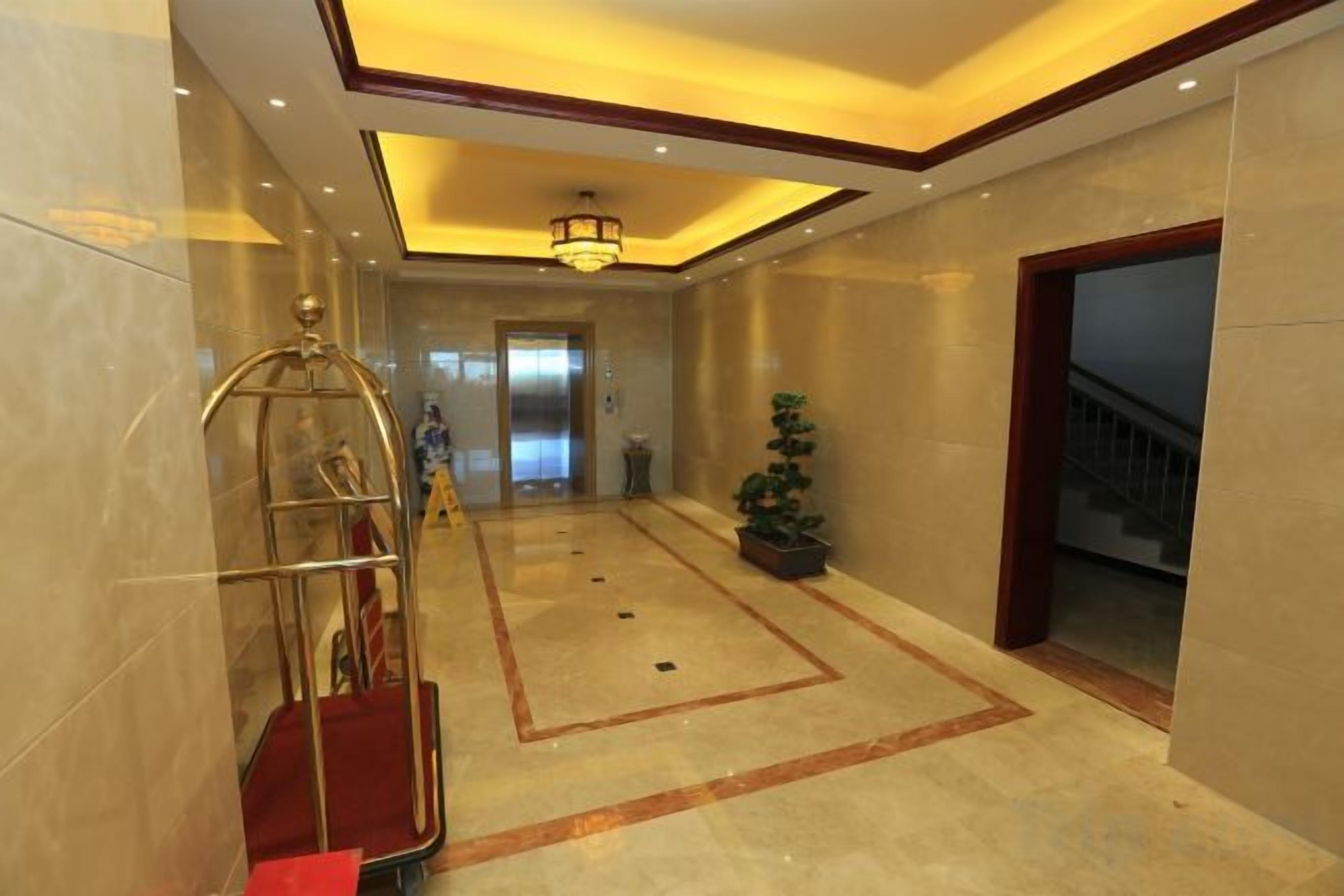 Un vestíbulo de hotel con alfombra roja, un mostrador de recepción, una araña y una escalera.