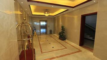 Un vestíbulo de hotel con alfombra roja, un mostrador de recepción, una araña y una escalera.