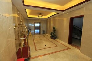 A hotel lobby with a red carpet, a reception desk, a chandelier, and a staircase. - Guang'anxin Hotel (Barkol)