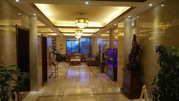 A hotel lobby with a marble floor, a chandelier, a sofa, a statue, and a large window. - Guang'anxin Hotel (Barkol)