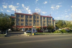 Um hotel de vários andares com telhado vermelho, estacionamento e céu claro.