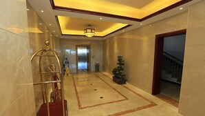 A hotel lobby with a marble floor, a reception desk, a staircase, and a chandelier. - Guang'anxin Hotel (Barkol)