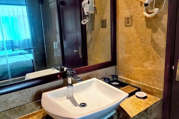A modern bathroom with a white sink, a mirror, and a hairdryer mounted on the wall. - Guang'anxin Hotel (Barkol)