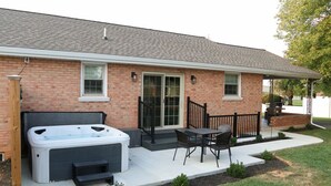 Una casa de ladrillo con un patio, un jacuzzi y mobiliario exterior.