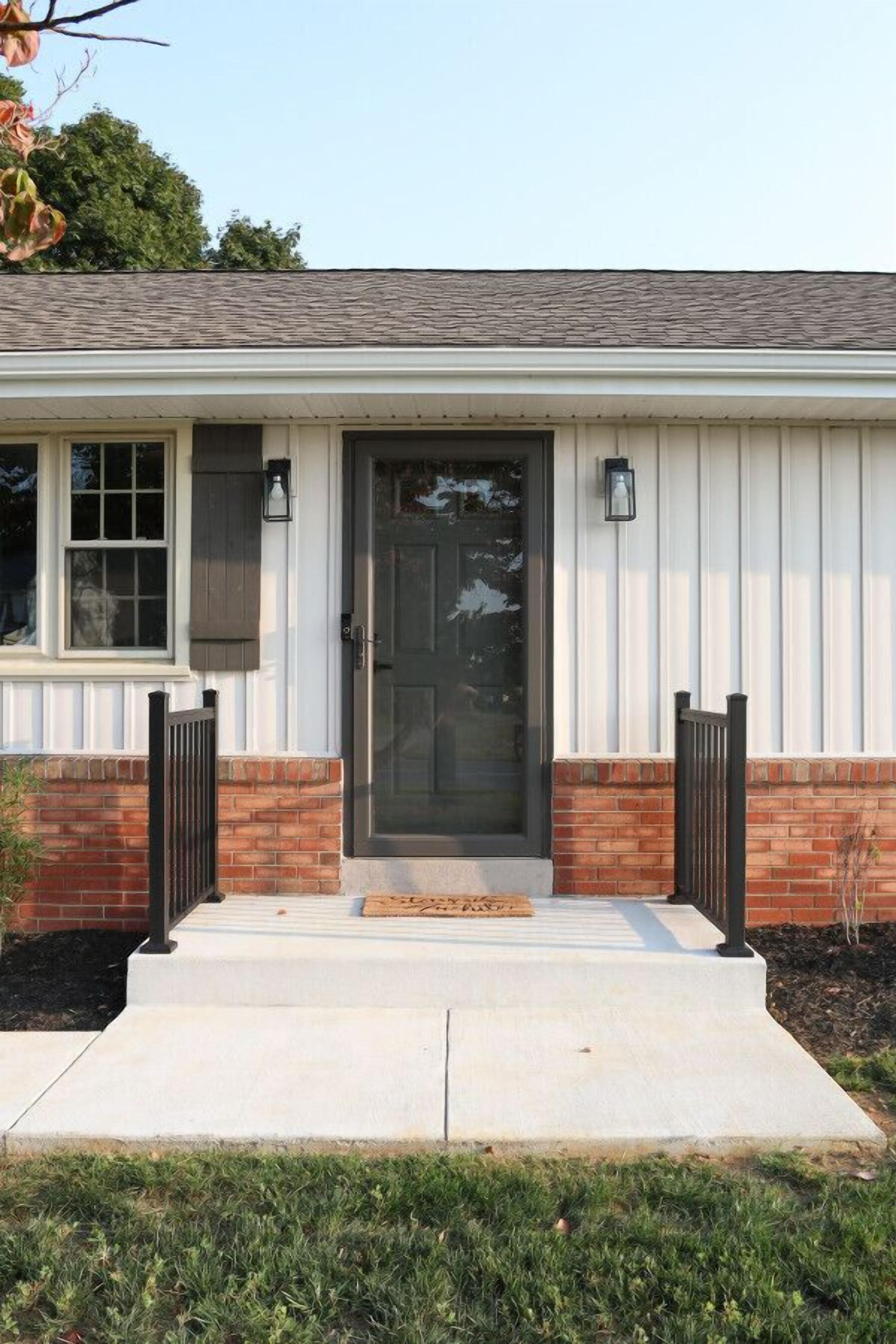 A single-story house with a front door, two windows, and a small porch.