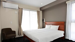 Ein Hotelzimmer mit einem Bett, einem Sessel, einer Klimaanlage und einem Telefon.