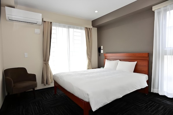 A hotel room with a bed, a chair, an air conditioning unit, and a telephone. - BRILLIANCE HOTEL (Nagoya)