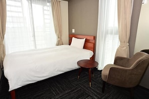 A hotel room with a large bed, a wooden headboard, a round table, and a brown armchair. - BRILLIANCE HOTEL (Nagoya)
