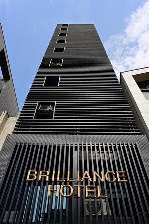 A tall building with a modern design, featuring a prominent sign for the Brilliance Hotel. - BRILLIANCE HOTEL (Nagoya)