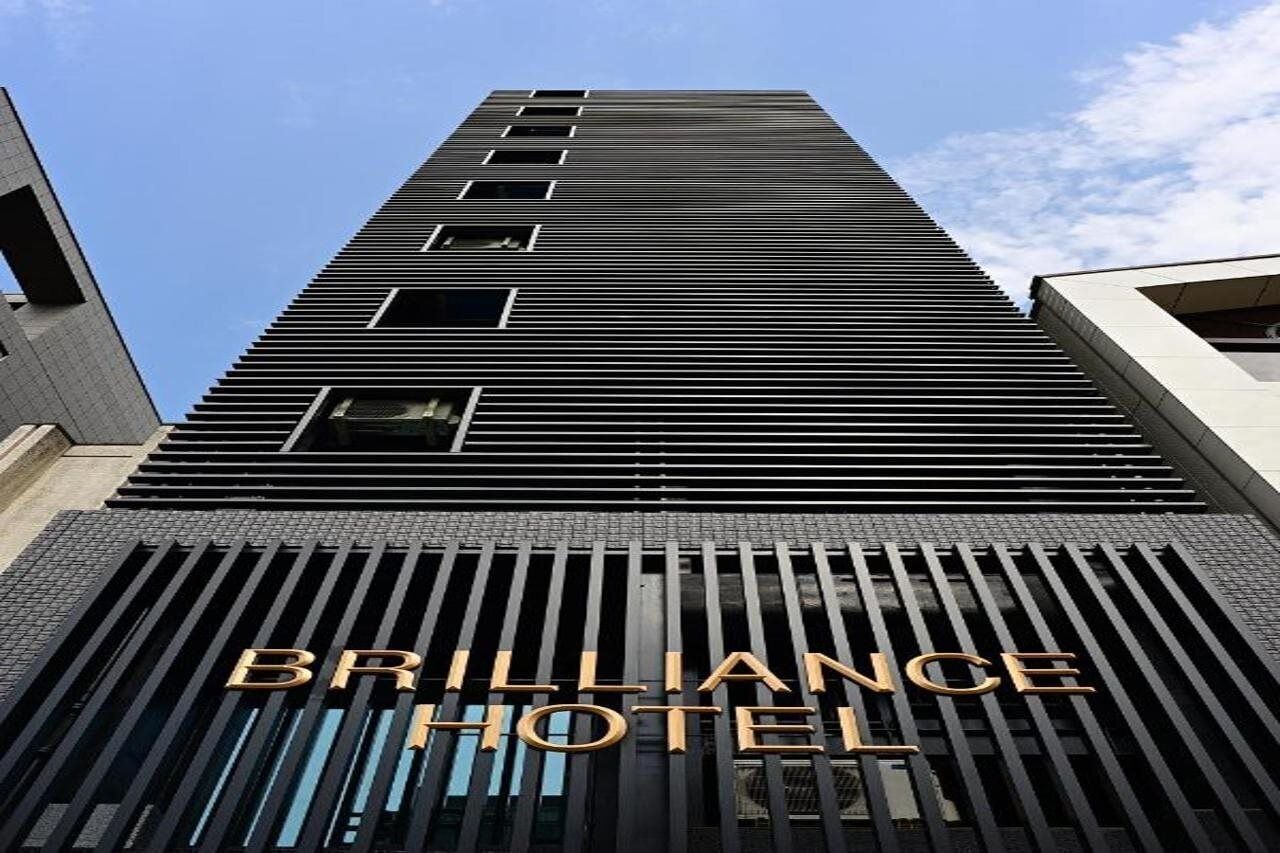 Un edificio alto de diseño moderno, con un llamativo letrero del Hotel Brilliance.