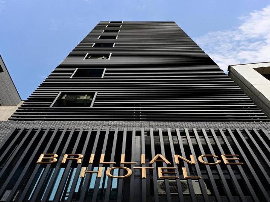 Un edificio alto de diseño moderno, con un llamativo letrero del Hotel Brilliance.