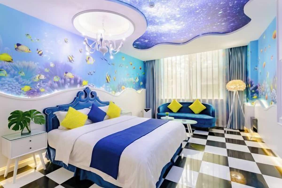 A hotel room with a bed, a blue sofa, a chandelier, and a checkered floor.