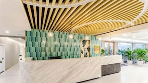 A modern reception desk with a green patterned wall and a wooden ceiling. - Hawaii Hotel (Leshan Jiaxing Road Food Street) (Leshan)