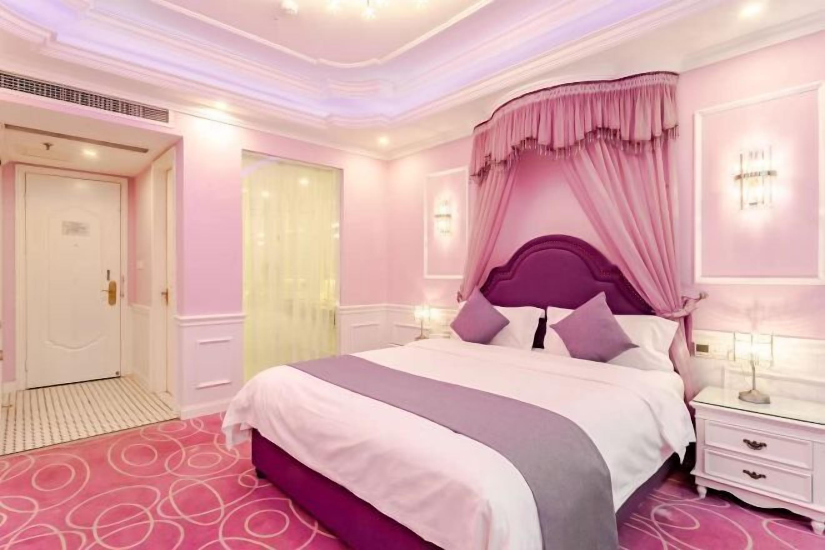 Un dormitorio con una cama grande, una mesita de noche y una ventana con cortinas.