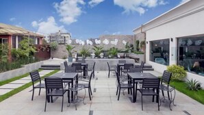 An outdoor patio with tables and chairs, surrounded by greenery and a clear sky. - Hawaii Hotel (Leshan Jiaxing Road Food Street) (Leshan)