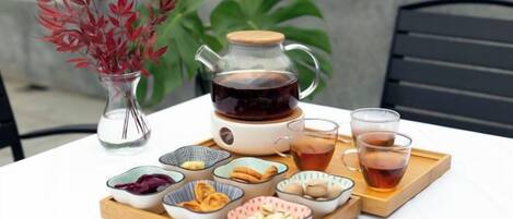 Una mesa con tetera, tazas y una bandeja de aperitivos.