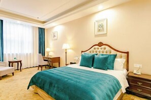 Une chambre d’hôtel avec un grand lit, un bureau, une chaise et une table de chevet.