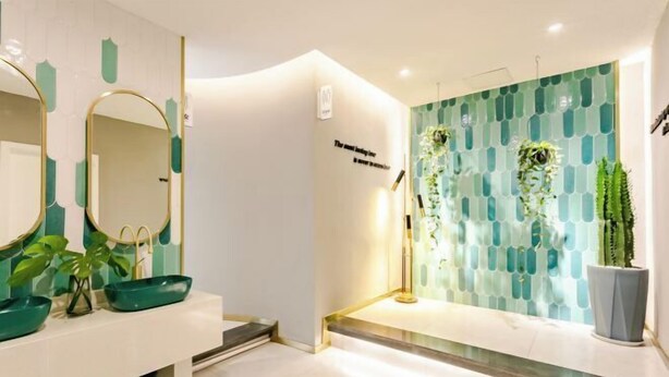 A modern bathroom with a white vanity, green decorative elements, and a wall-mounted mirror. - Hawaii Hotel (Leshan Jiaxing Road Food Street) (Leshan)